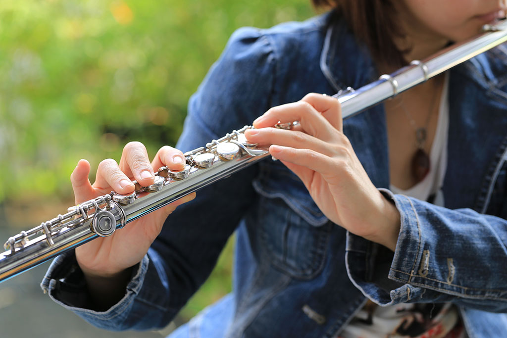 Flute Teacher in Brighouse playing flute in denim jacket